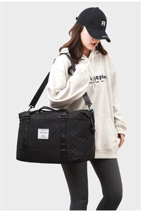 Detailed view of black quilted travel bag featuring Life Long logo and nylon shoulder strap