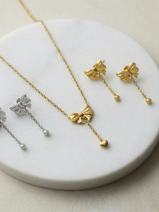 Detailed view of elegant gold and silver bow jewelry set on white marble tray