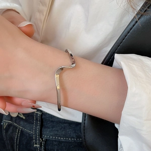 Detail of silver wavy irregular open cuff bracelet on wrist for a minimalist modern look