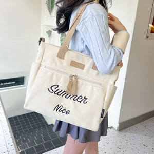 Detailed side view of beige canvas tote bag with brown straps worn by a model