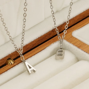 Macro detail of silver initial pendants in a luxury velvet jewelry box on O-chain
