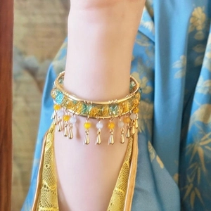 Elegant Chinese style golden open bangle with tassels and colorful beads on wrist