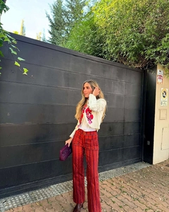 Close-up of white knit cardigan and striped pants on a model in an outdoor urban setting
