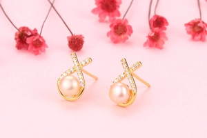 Detail of S925 silver earrings with freshwater pearl and zircon in X-shaped gold setting