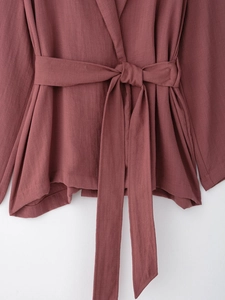 Detail of dusty rose textured fabric with matching waist belt on a stylish wrap top