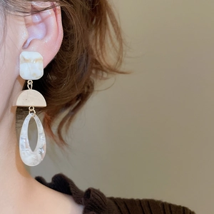 Close-up of retro geometric resin teardrop earrings worn with vintage style