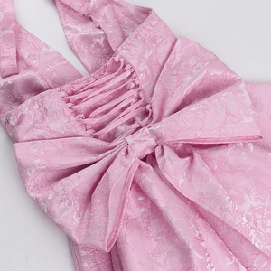 Detail of pink jacquard dress showing back cross-straps and large bow tie decoration