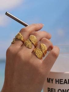 Detail of gold leaf texture rings on hand during outdoor resort style photoshoot