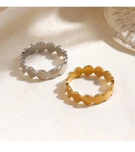 Detailed view of wave-shaped geometric gold and silver stainless steel rings on fabric