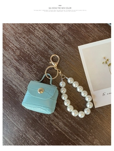 Detail of mint green crocodile texture mini bag keychain with pearls on wood