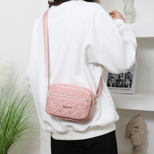 Pink quilted oxford fabric crossbody bag with gold hardware and embroidery details