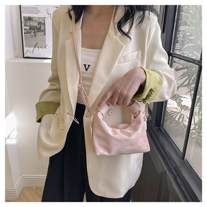 Detail of light pink pleated crescent bag with satin finish and golden hardware
