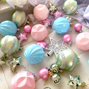 Close-up of pastel Christmas ornaments featuring light green and pink textured star shapes