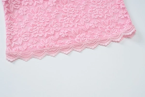 Gros plan sur un tissu en dentelle rose avec motifs floraux et bordure festonnée