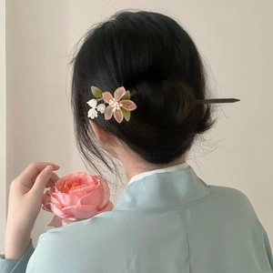 Detail of pink flower hair pin styled in a bun on a woman wearing traditional blue dress