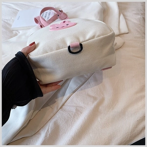 Close-up of cream canvas kids backpack with pink straps and cute rabbit patch detail