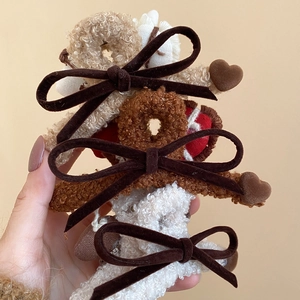 Close-up of plush hair claws with brown velvet bows and hearts in warm autumn colors
