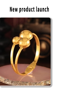 Detail of a gold layered bangle with three spherical beads on a pink stone base