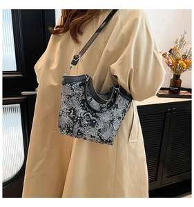 Close-up of black and white floral embroidery on a chic crossbody bucket bag with leather strap