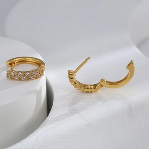 Detail of gold-plated brass hoop earring showing white zircon inlay and clasp mechanism