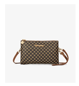 Detailed shot of a brown crossbody bag with gold circle patterns and metal logo pendant