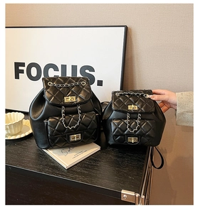 Detailed view of black quilted leather backpacks with golden metal twist locks and chains