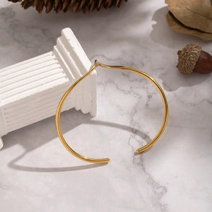 Detailed view of an 18K gold plated stainless steel cuff with a sharp V-shape geometric tip