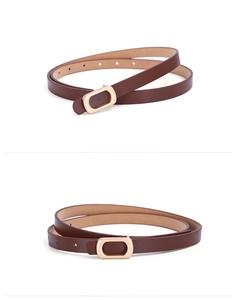 Macro detail of slim dark brown PU leather belt with polished gold oval metal buckle