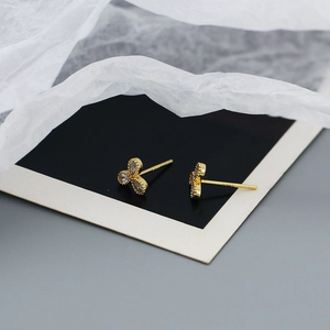 Macro view of gold clover earrings featuring pear-cut cubic zirconia and beaded edge detailing