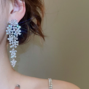 Macro shot of silver flower tassel earrings with zircons showing sparkle on a model