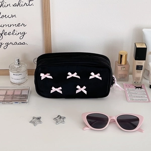 Detail view of the black makeup bag with pink bow pattern and functional dual zippers