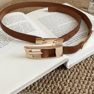 Detail of vintage brown leather belt with gold buckle over an open book for classic style