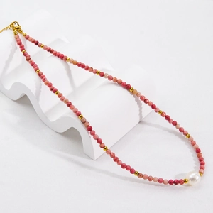 Detail of natural pink rhodochrosite beads and a large white pearl on an elegant necklace