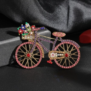 Detailed view of a vintage bicycle brooch with colorful rhinestones on black silk fabric