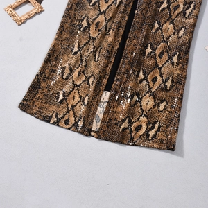 Nahaufnahme von Schlangenprint-Pailletten und Schlitz-Detail am Saum eines Minirockes