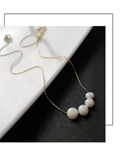 Detail view of four natural white pearls on a delicate gold titanium steel chain