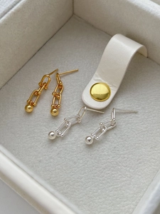Detail of silver and gold U-shaped link earrings with metal balls on velvet lining