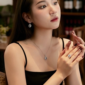 Elegant silver jewelry set with light blue oval gemstones worn by model in soft lighting