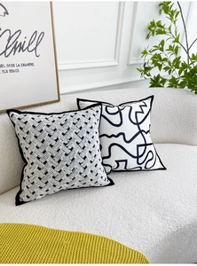 Detail of woven velvet cushions with black and white patterns on a beige sofa