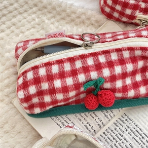 Detail of red cherry plaid knit pencil case featuring zipper closure and soft texture