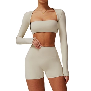 Three-piece beige yoga set with long sleeve zip jacket, bandeau top, and high-waist shorts