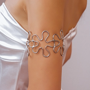 Close-up of a silver hollow wavy flower upper arm cuff bracelet on a female arm