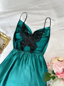 Détail d'une nuisette en satin vert foncé avec applique papillon en dentelle noire
