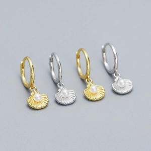 Macro detail of shell drop earrings with pearls in gold and silver finish