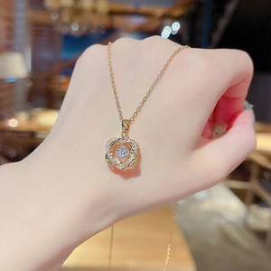 Vista macro di una collana dorata con ciondolo a cuore geometrico e cristalli incastonati