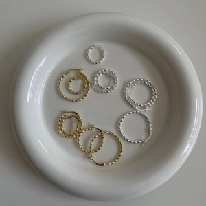 Detail showing S925 hallmark on gold and silver beaded hoop earrings in a ceramic tray