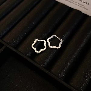 Elegant silver irregular wavy flower hoop earrings on a black velvet jewelry tray
