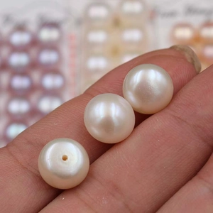 Three lustrous white freshwater button pearls displayed on hand for jewelry making