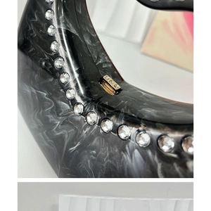Macro shot of marble textured acrylic clutch with sparkling rhinestone edge detailing