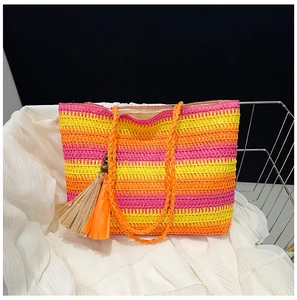 Detail of colorful rainbow striped straw tote bag with textured tassels and woven handles